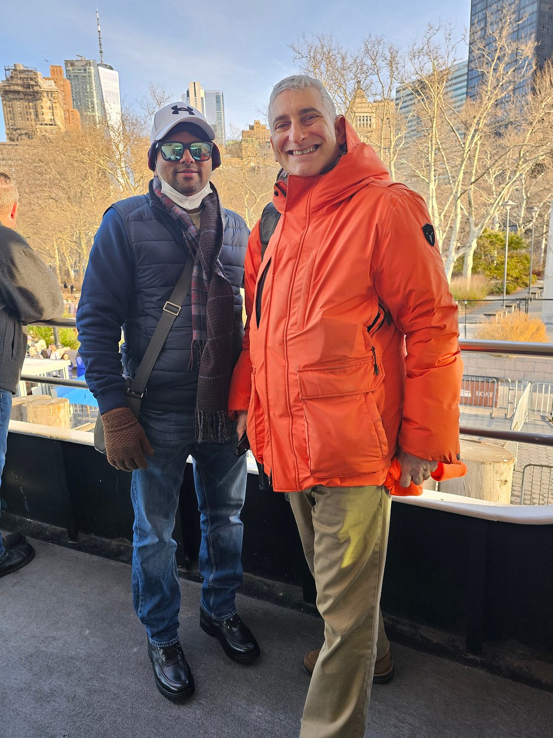 Jared with a guest at Battery Park with the Statue of Liberty ferry landing behind them