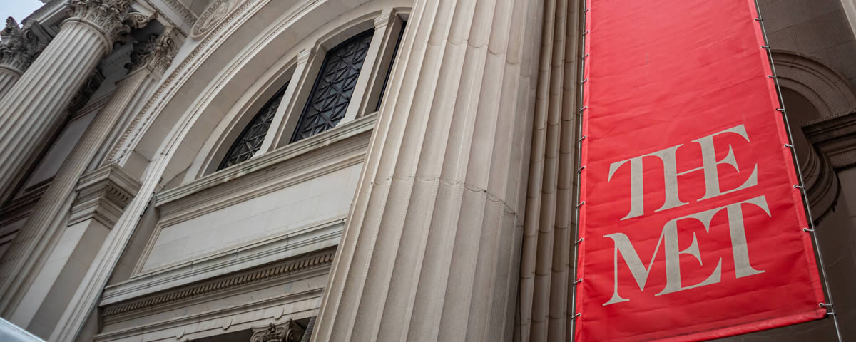 The red 'The Met' banner hanging on the Metropolitan Museum of Art facade on Fifth Avenue